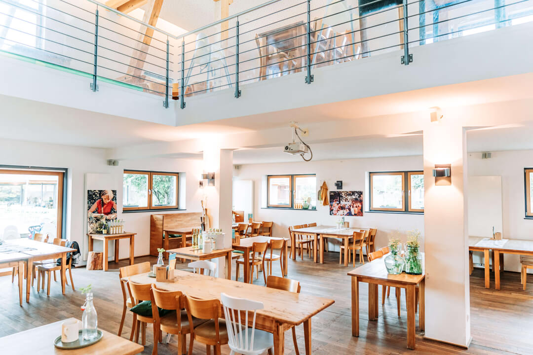 Lichte restaurantzaal met houten tafels bij Gut Hügle