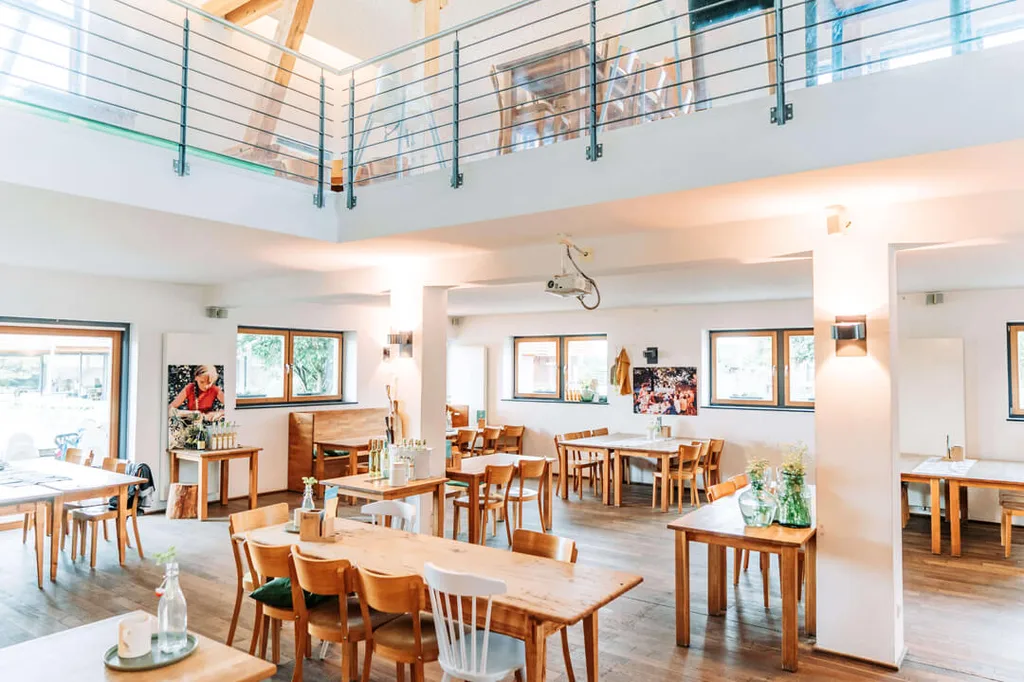 Lichte restaurantzaal met houten tafels bij Gut Hügle